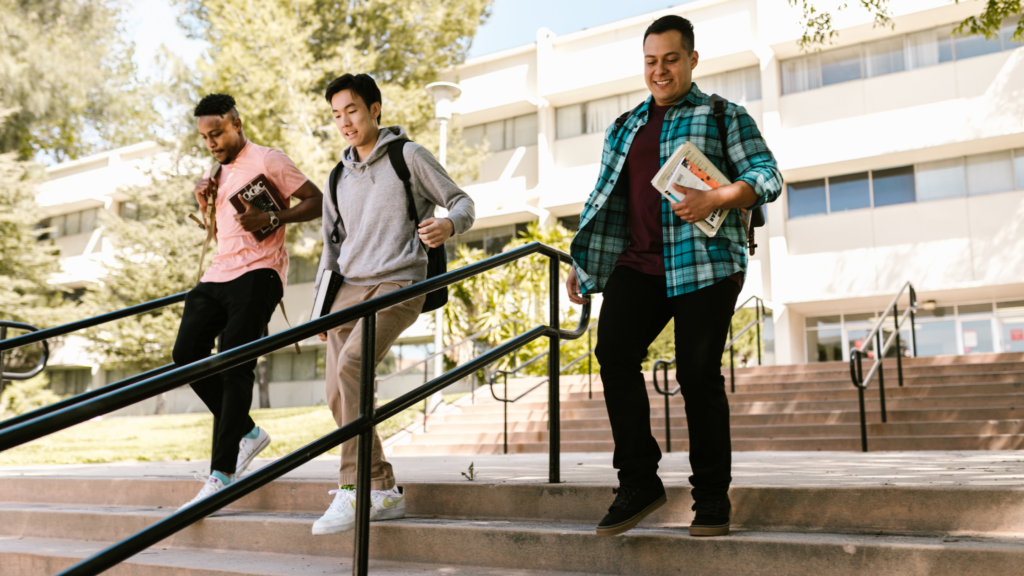 Three young men walking down the stairs outside a college building